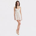 Woman wearing a white lace dress on a light gray background