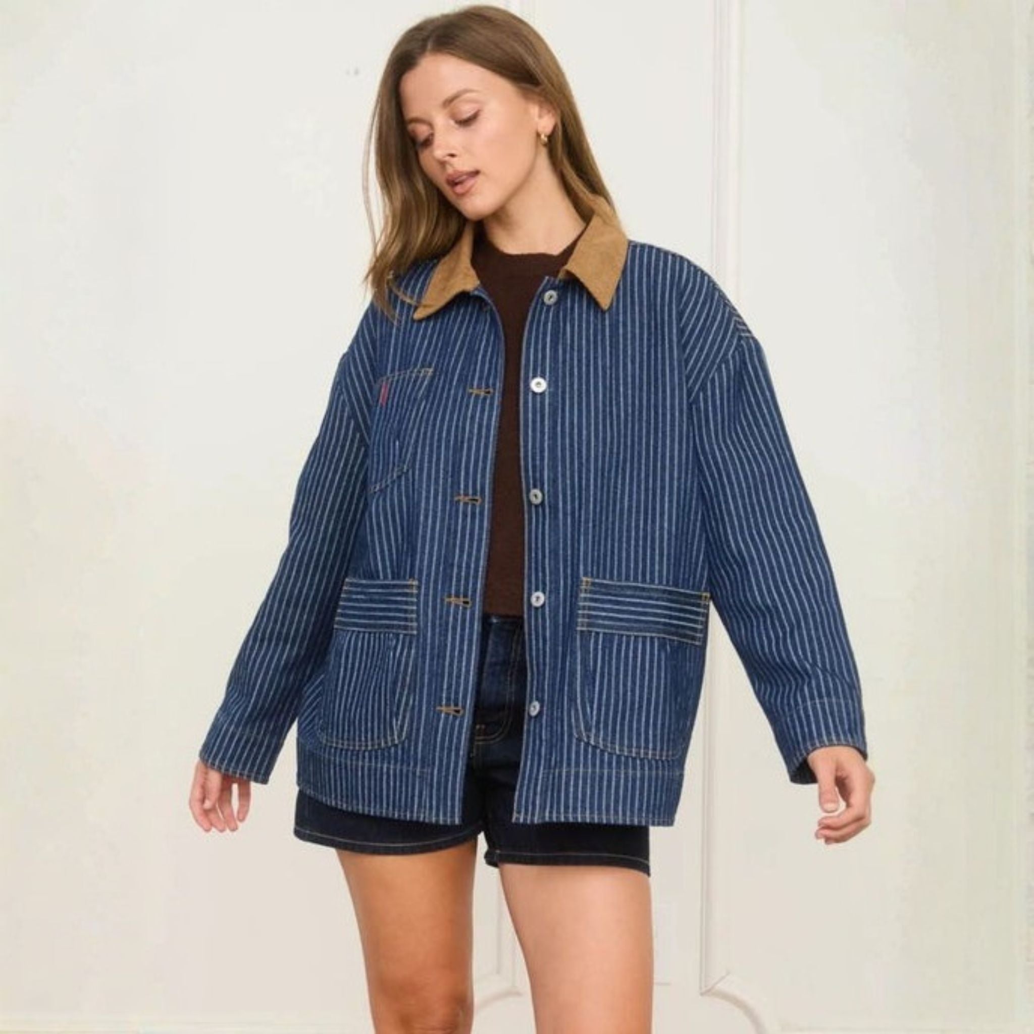 Woman wearing a blue striped jacket with a brown collar against a white background