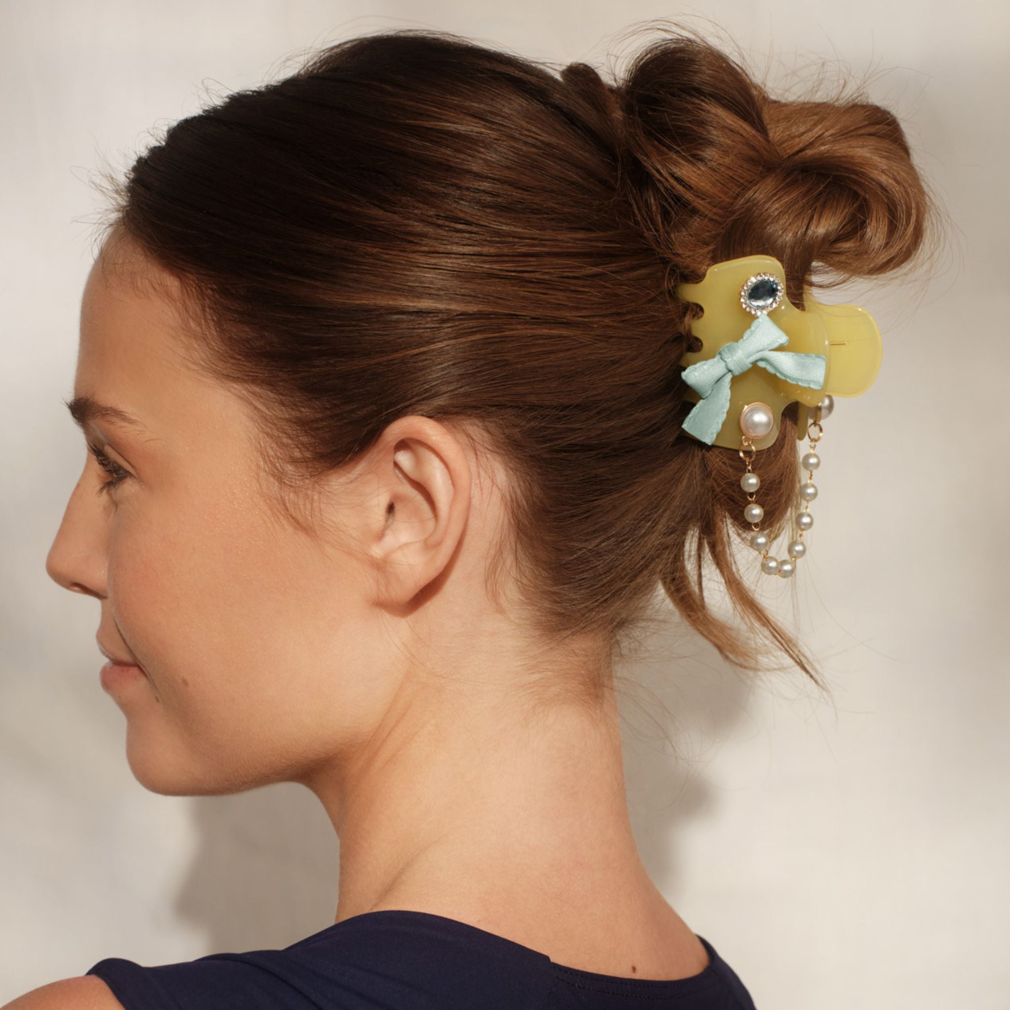 Woman with a decorative hair clip in her bun against a neutral background