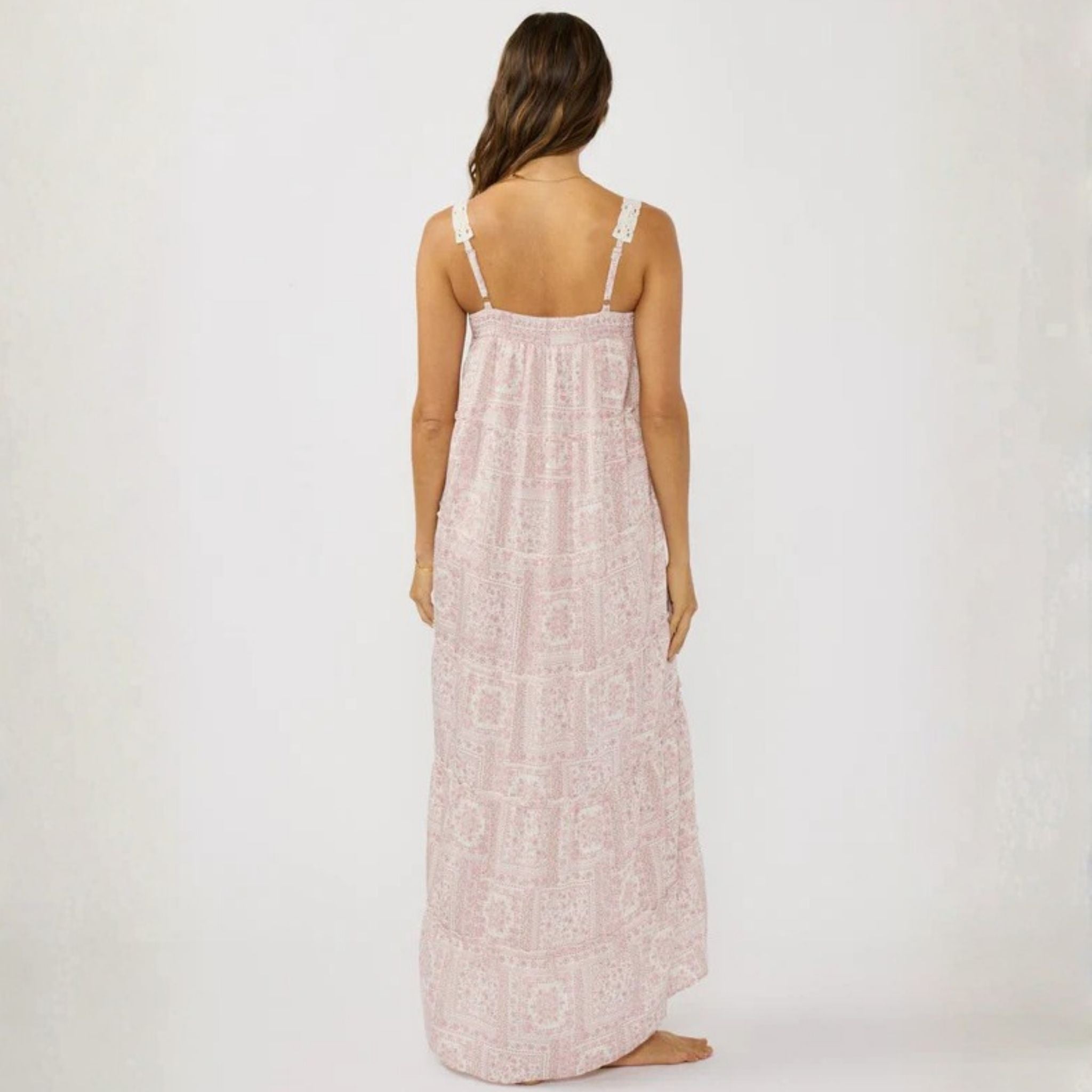 Woman wearing a long, light pink dress with thin straps on a white background