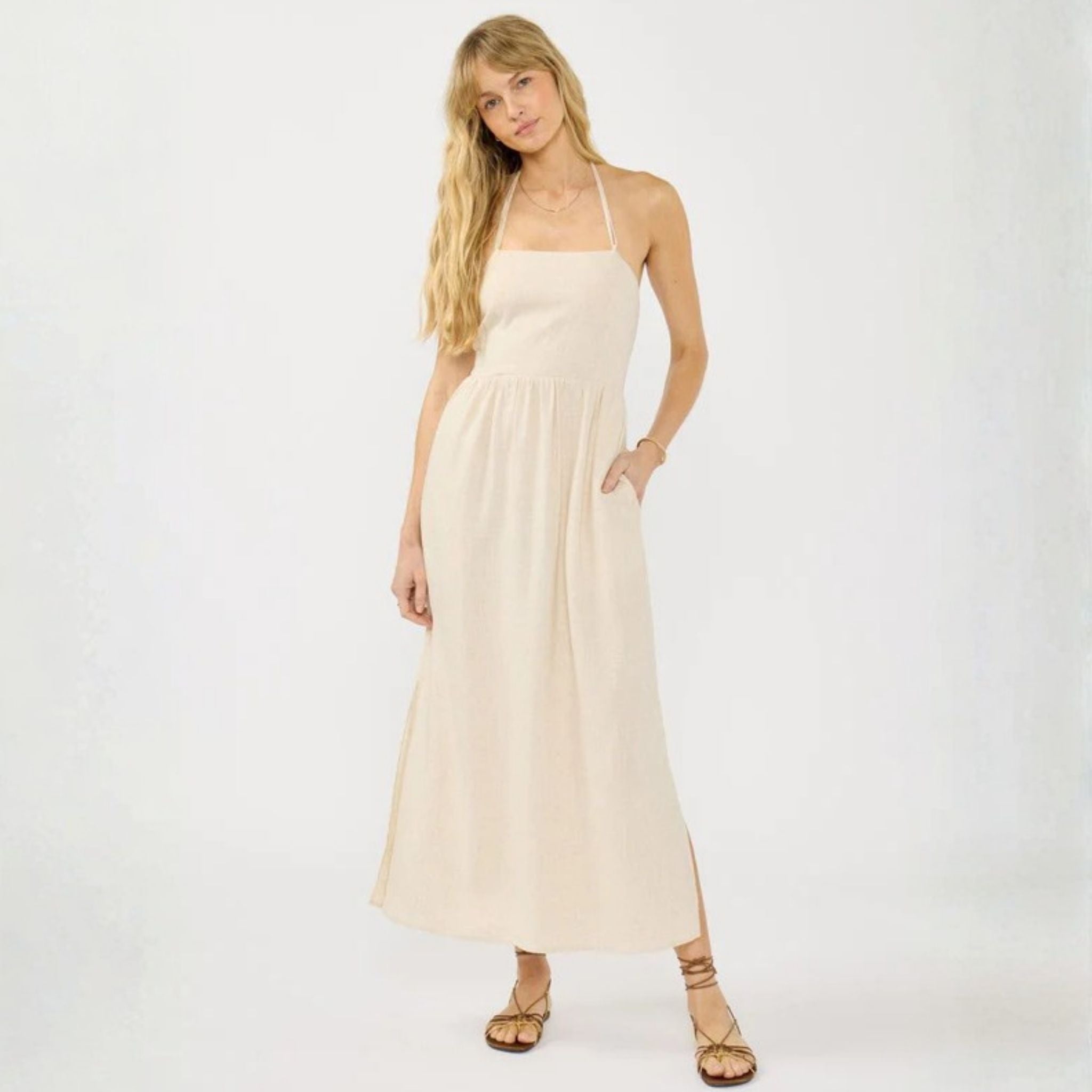 Woman wearing a beige halter neck dress on a white background