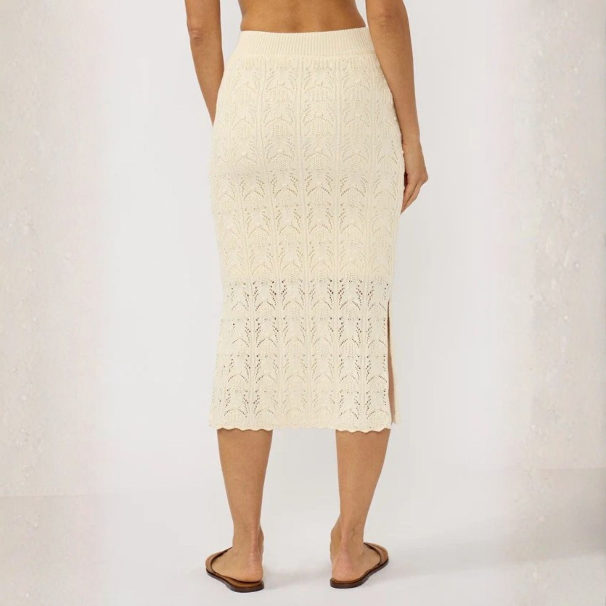 Person wearing a cream-colored knit skirt on a plain background