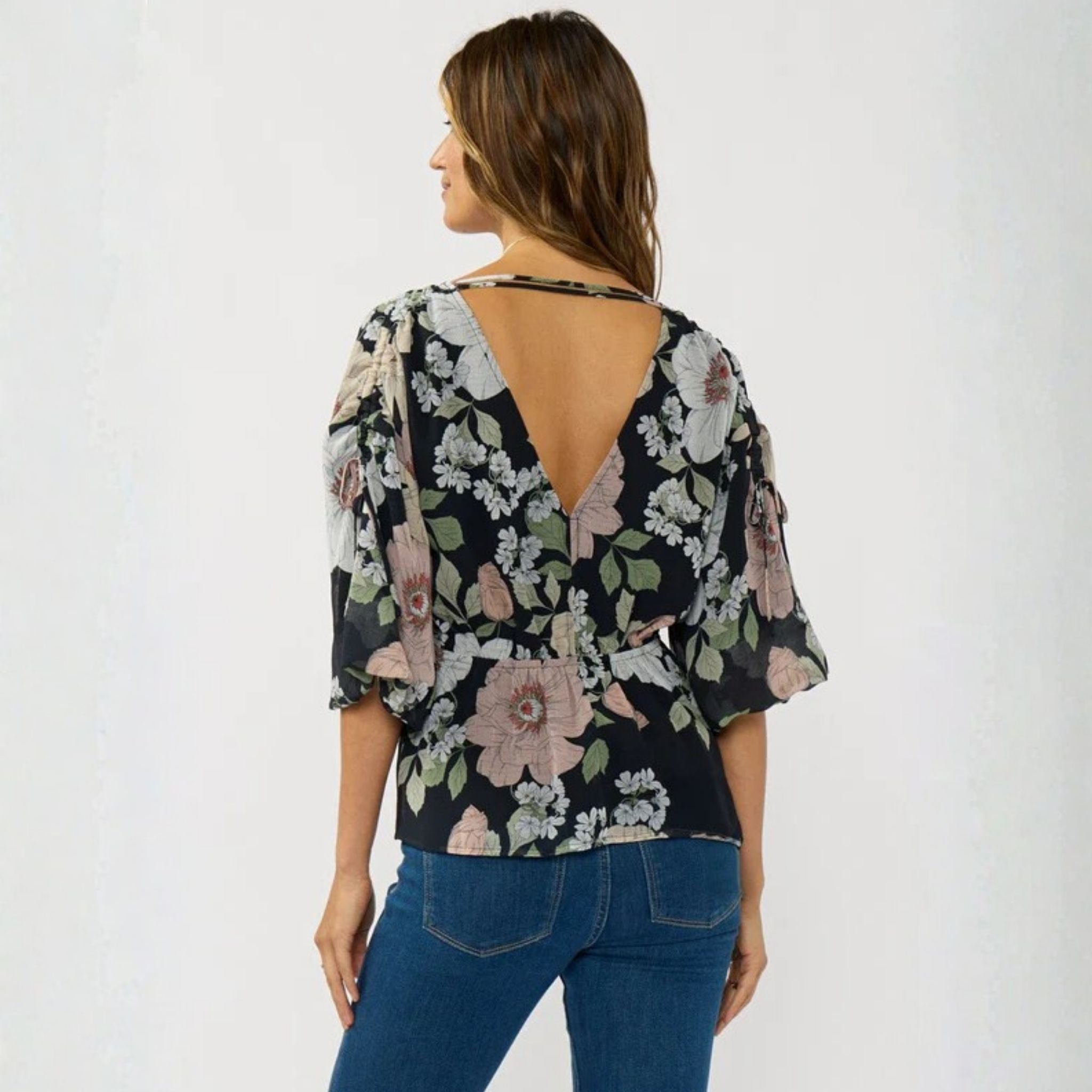Woman wearing a floral blouse with a backless design on a white background