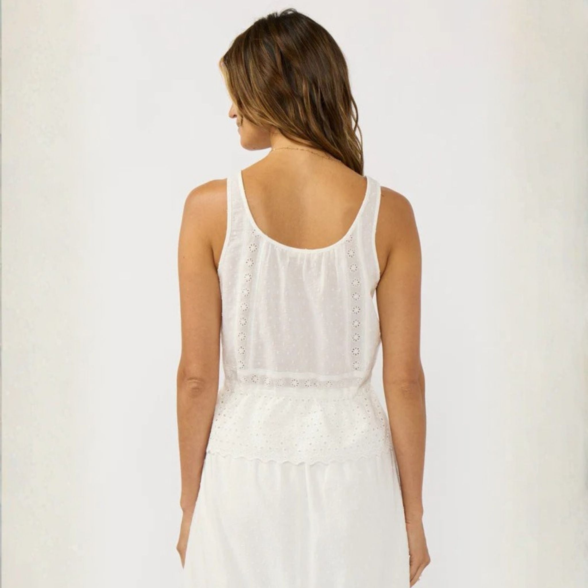 Woman wearing a white sleeveless dress against a plain background