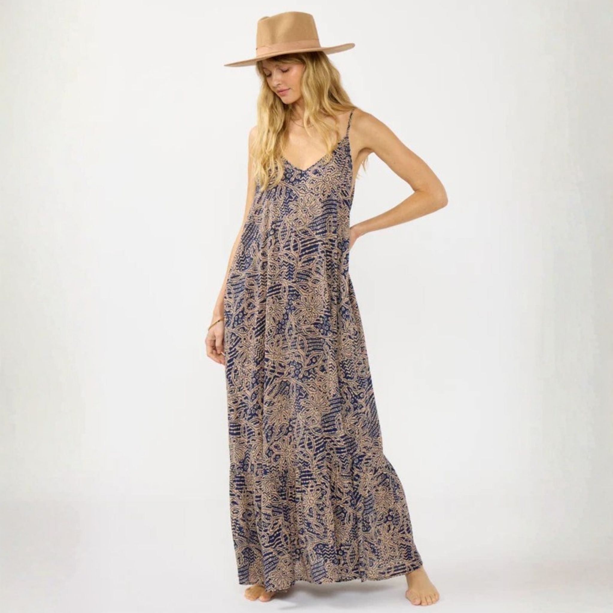 Woman wearing a long patterned dress and a hat on a white background