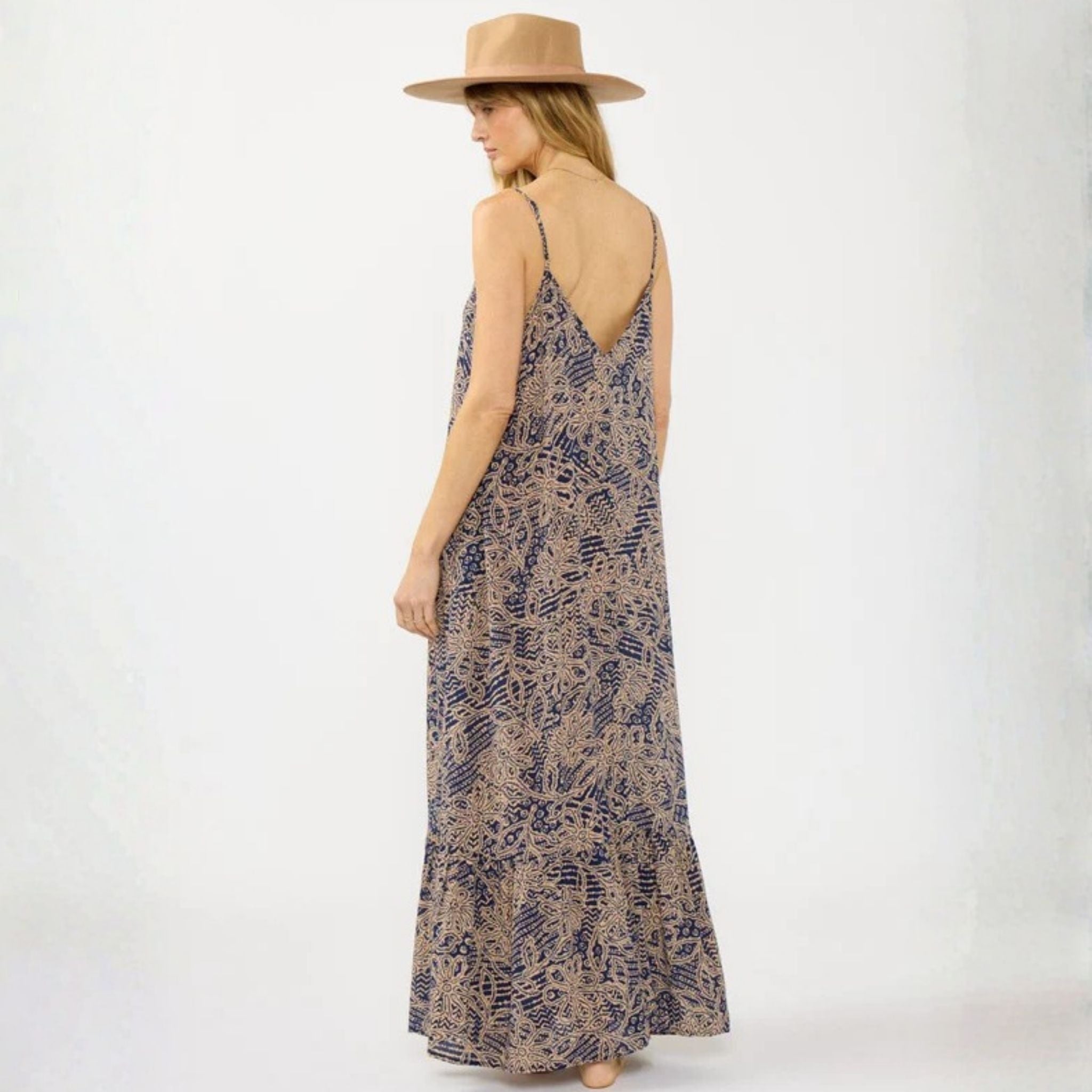 Woman wearing a patterned dress and beige hat on a white background