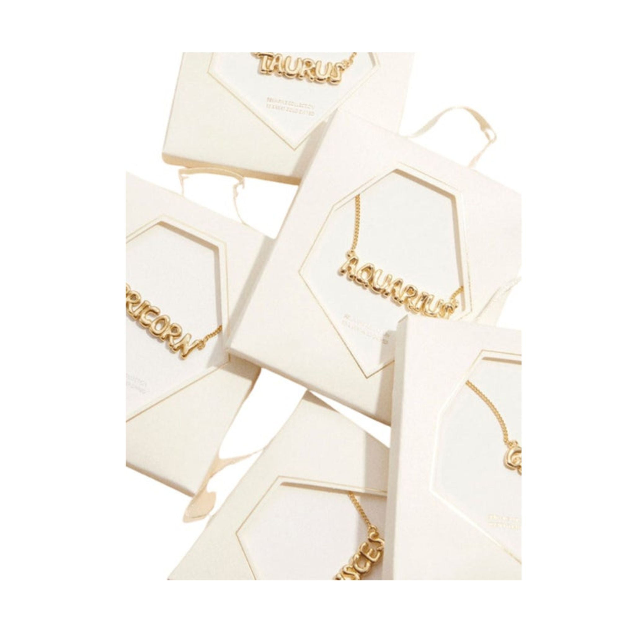 Gold necklaces in branded boxes on a white background